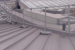 Metal roof guardrails with mesh panels on a standing seam roof